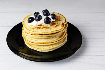 Blueberry pancakes on black plate on white board table