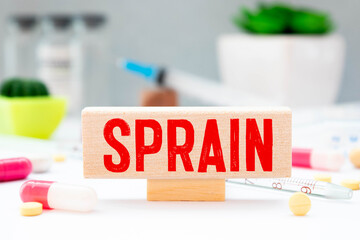 Medicine concept. On a reflective white surface lies a stethoscope and cubes with the inscription - SPRAIN.