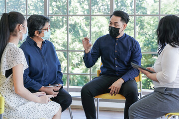 focus group of mental health by psychologist consultant. Asian people with face mask meeting together to talk problem and receive mental treatment. Man doctor leader speaking to diversity patients. - Powered by Adobe