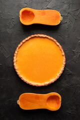 Pumpkin pie with cutted butternut squash on dark plaster background