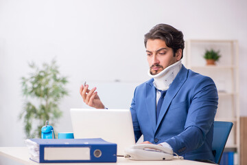 Young male employee after accident sitting at workplace
