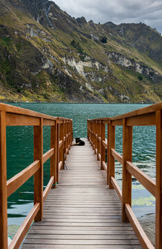Black dog resting at the end of a wooden dock at Quilotoa Lake in the Andes Mountains of Ecuador