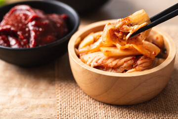 Korean kimchi cabbage eating by use chopsticks and gochujang (red chili paste) on wooden background