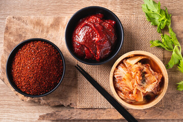 Korean kimchi cabbage with gochujang (red chili paste) and chili powder in bowl on wooden...
