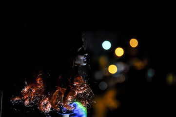 Silhouette of a female face on a light background. SIlhouette of a lonely doll with long hair at night with backlight of city view from window