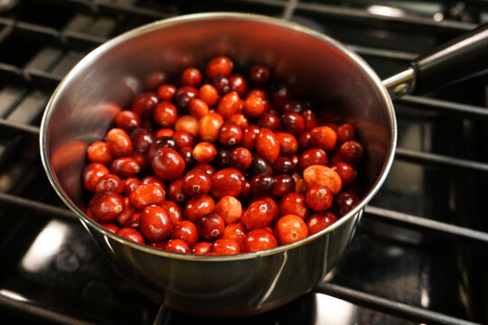 Fresh, raw red cranberries, ready for making the traditional USA Thanksgiving cranberry sauce, closeup isolated on stovetop background.