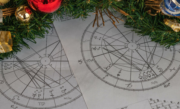Printed astrological natal charts with Christmas decorative arrangement in the background