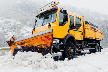 Moving snow plow truck removing snow from a snowy road.