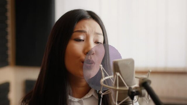 Hit Maker. Beautiful Young Asian Woman Singing To Professional Microphone In Studio