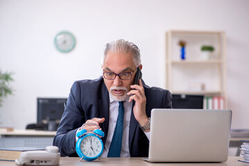 Old male employee in time management concept