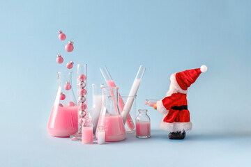 Laboratory of pink Christmas baubles with Santa Claus against blue background.  Scientific and creative New Year concept.