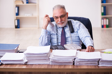 Old businessman employee unhappy with excessive work in the office