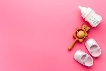 Baby newborn pink booties with bootle of milk and wooden toy