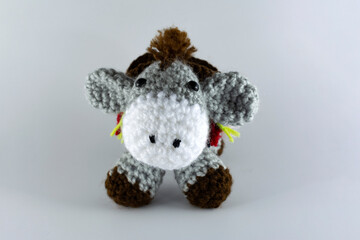 Small-eared donkey with its brown saddlebag. Crochet stuffed animal