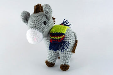 Lead-colored donkey with its saddlebag. Crochet stuffed animal