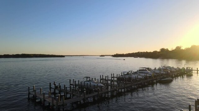 sun setting over the horizon with a boat sailing at Lake Minnetonka, cinematic aerial view