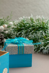 Naklejka na ściany i meble vertical photo of Christmas background with a silver gift with blue bow and green garland
