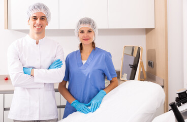 Portrait of young confident man and woman doctors in interior of clinic of aesthetic medicine