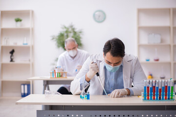 Naklejka premium Two male chemists working at the lab during pandemic