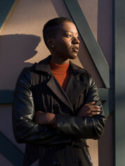 Portrait of a young woman in a black coat and orange mock turtleneck shirt