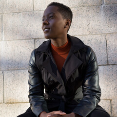 Portrait of a young woman in a black coat and orange mock turtleneck shirt