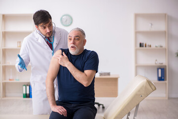 Obraz premium Old male patient visiting young male doctor in vaccination conce