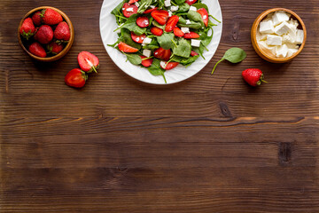 Green spinach salad with red strawberry and goat cheese, top view