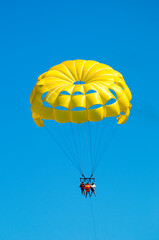 Back view of a Yellow parasailing  with 3 people in Punta Cana. Clear sunny blue sky day