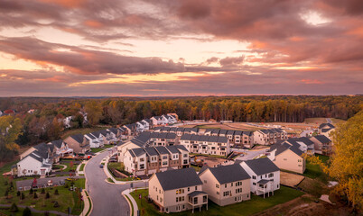 Aerial view of large multi unit American real estate development in Maryland with single family homes lining the main street, townhomes springing up in the background and many lots still empty