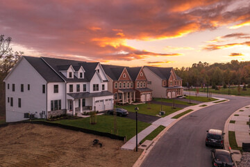 New American single family homes with vinyl and brick facade on a newly built neighborhood street with colorful dramatic sunset sky in the east coast USA