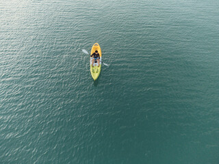Unidentified man on sea Kayaker Aerial View during sunset. Caucasian Sportsman in the Yellow and Blue Kayak Paddling on the Scenic sea Along the Shore. © chayakorn