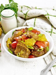 Meat with oranges in bowl on wooden table