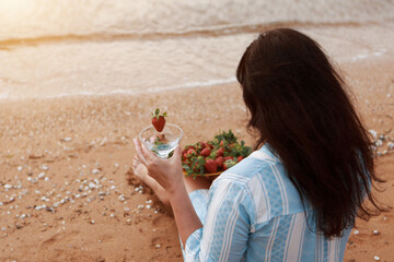 Diet. Healthy eating and rest. woman drinks clean water in glass background sea and eats strawberries. A woman on the beach enjoys life
