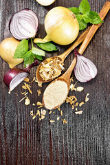 Onion powder and flakes in spoons on dark board top