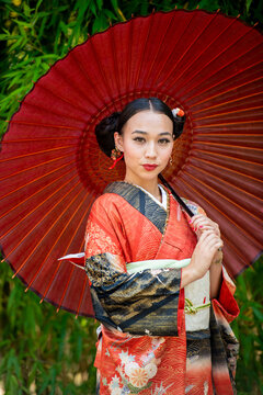 Portrait of woman wearing kimono and holding parasol