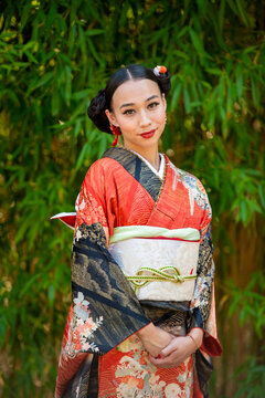 Portrait of smiling woman wearing kimono standing in park