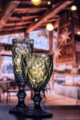 Sparkling Christmas and New Year lights glasses made of curly blue glass. Shining glasses with bright lights create a festive atmosphere and a desire to celebrate Christmas and New Year.