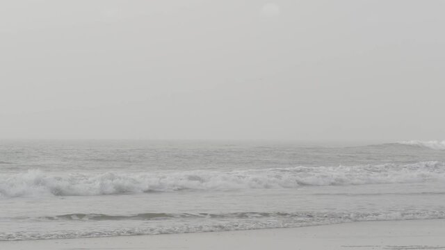 Sandy misty beach, Encinitas California USA. Pacific ocean coast, dense fog brume, empty sea shore. Coastline near Los Angeles, milky smog haze. Gloomy weather on shoreline. Grey monochrome water wave