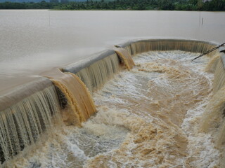 Brown water in the dam overflowing into the spillway , Flood in rainy season, Thailand