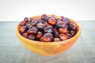 Chestnuts in a wooden bowl on textile backgound
