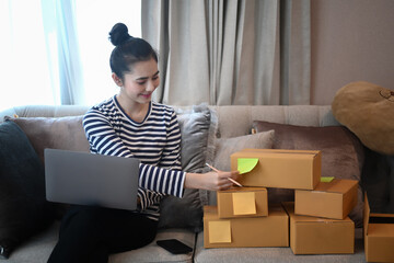 Startup small business entrepreneur checking order on laptop and preparing parcel boxes for delivery.