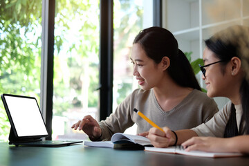 Happy mother and daughter  studying online and doing homework together at home.