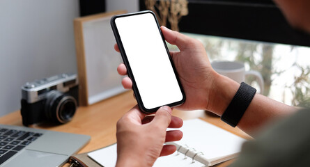 Young man sitting in home office and using smart phone.