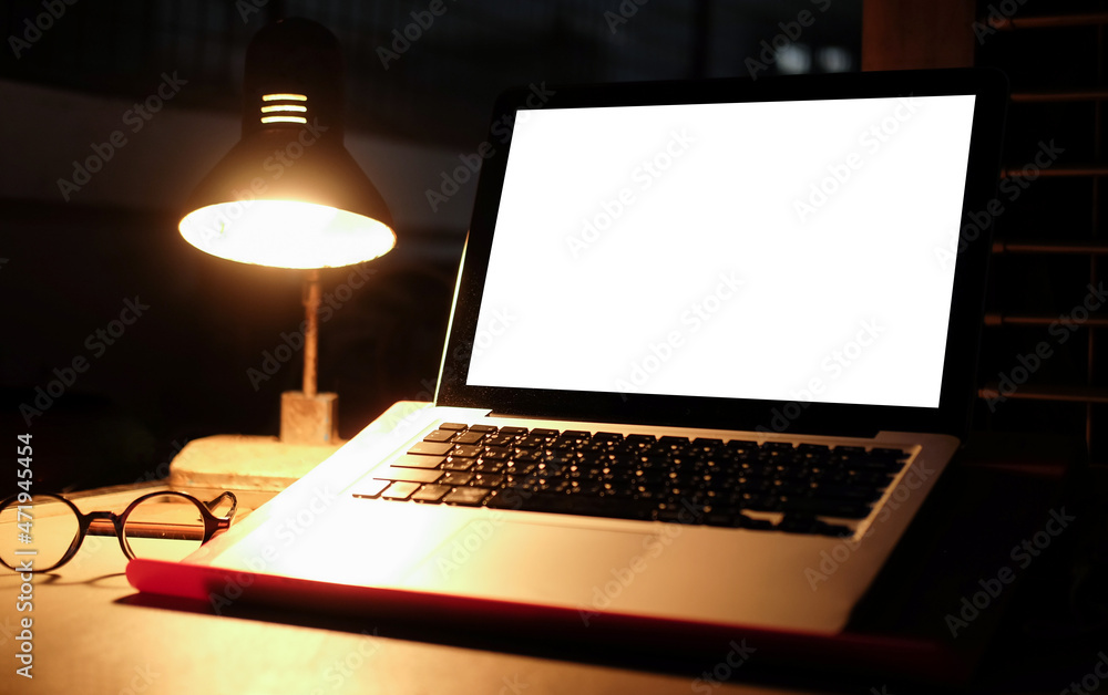 Poster Mock up computer laptop with empty display and glowing lamp on wooden table in dark room.