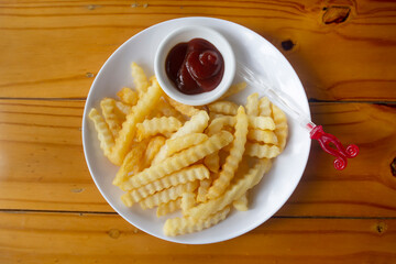 French fries serve on white dish with ketchap.