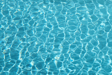 blue blurred textured swimming pool water surface waving motion by wind blow at noon sunshine
