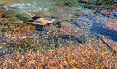 Fototapeta na wymiar young man swimming underwater in flowing river clear water at morning from top angle