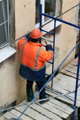 Fototapeta premium Workers erect scaffolding to repair the facade of a building