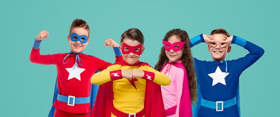 Company of brave superhero kids in studio - obrazy, fototapety, plakaty