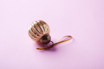 Christmas golden bauble on bright paper background. Close up. Copy space. 